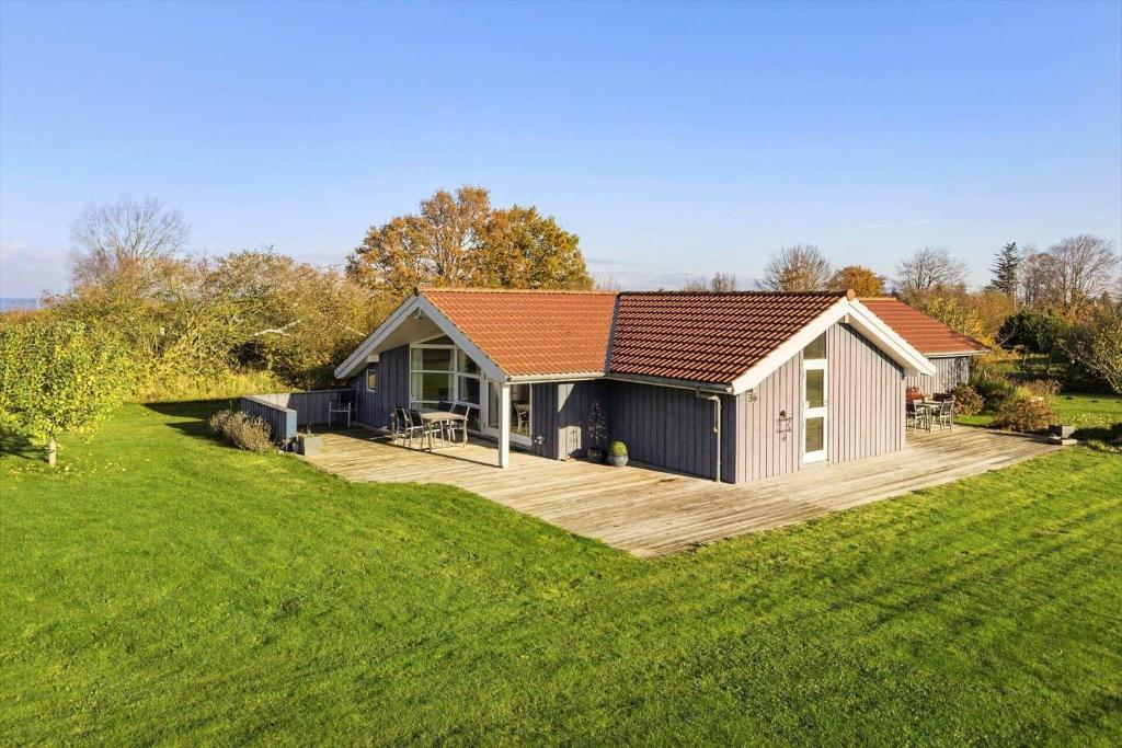 a small house with a wooden deck in a field at SB110-Nordborg-Sostjerneparken-36 in Nordborg
