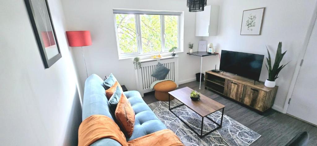 ein Wohnzimmer mit einer blauen Couch und einem Fernseher in der Unterkunft Corby Stay 2BR Work Trips & Family Friendly in Corby