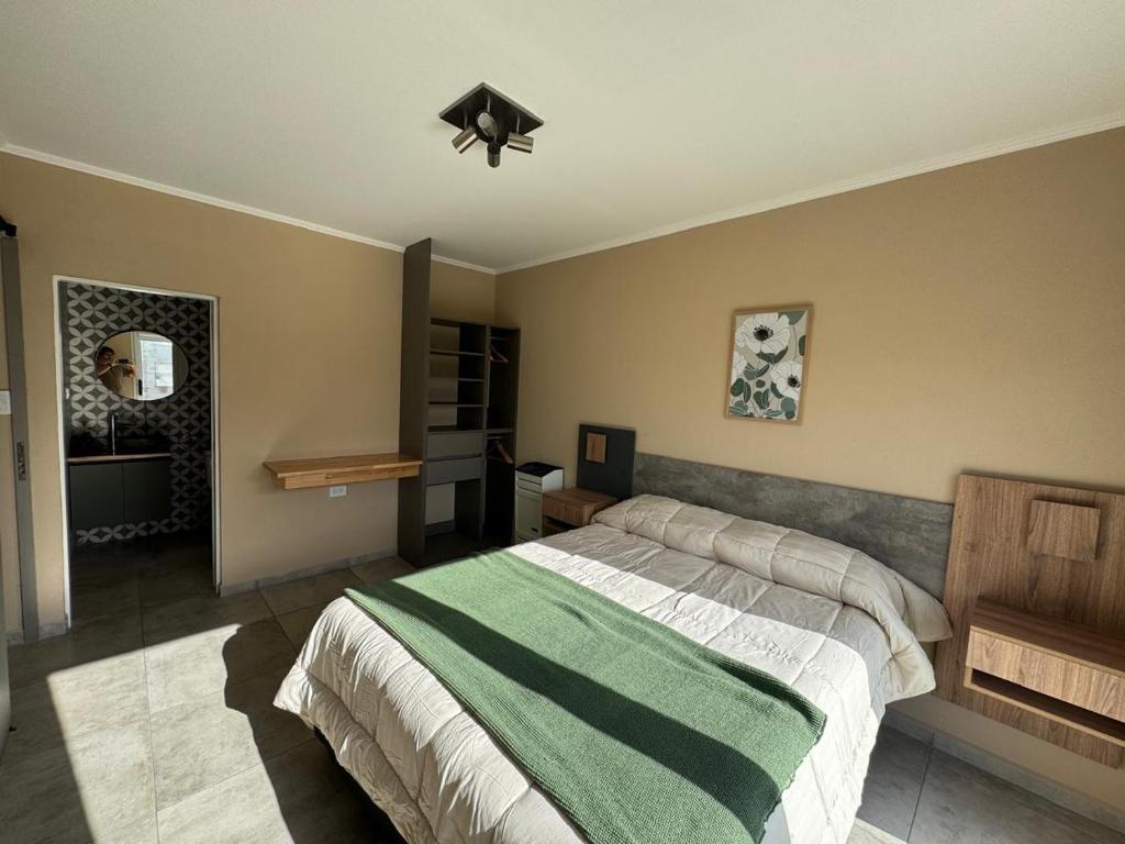 - une chambre dotée d'un lit avec une couverture verte et blanche dans l'établissement Cabañas Agapanthus Las Marias, à Tandil