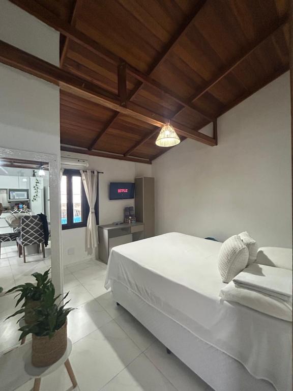a bedroom with a white bed and a living room at Flat 300m da Praia e Roda Gigante 2 andar com jacuzzi privativa in Balneário Camboriú