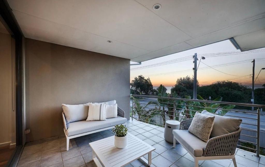 a balcony with two chairs and a couch and a table at 4 bed beachfront home in Sandringham w Spa and sunset views in Black Rock North