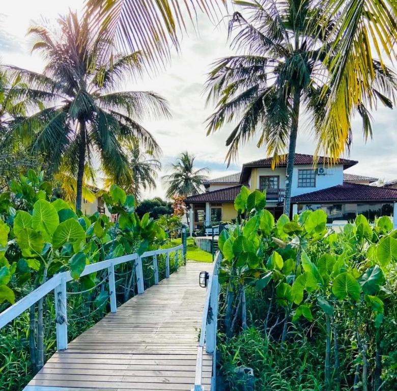 a wooden boardwalk leading to a beach with palm trees at Apartamento Em frente a praia - Piscina condomínio América Praia, acesso privativo para a praia in Porto Seguro