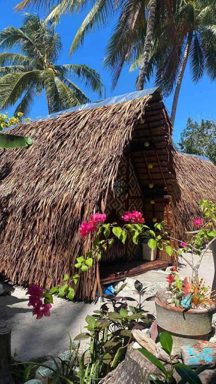a thatch roofed house with flowers and palm trees at Jonny's Hostel in San Juan