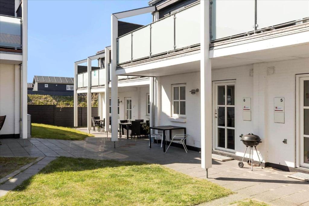 - une terrasse dans un bâtiment blanc avec une table et des chaises dans l'établissement TV1280-Bindslev-Tannisbugtvej-49-D-Nr-5, à Bindslev