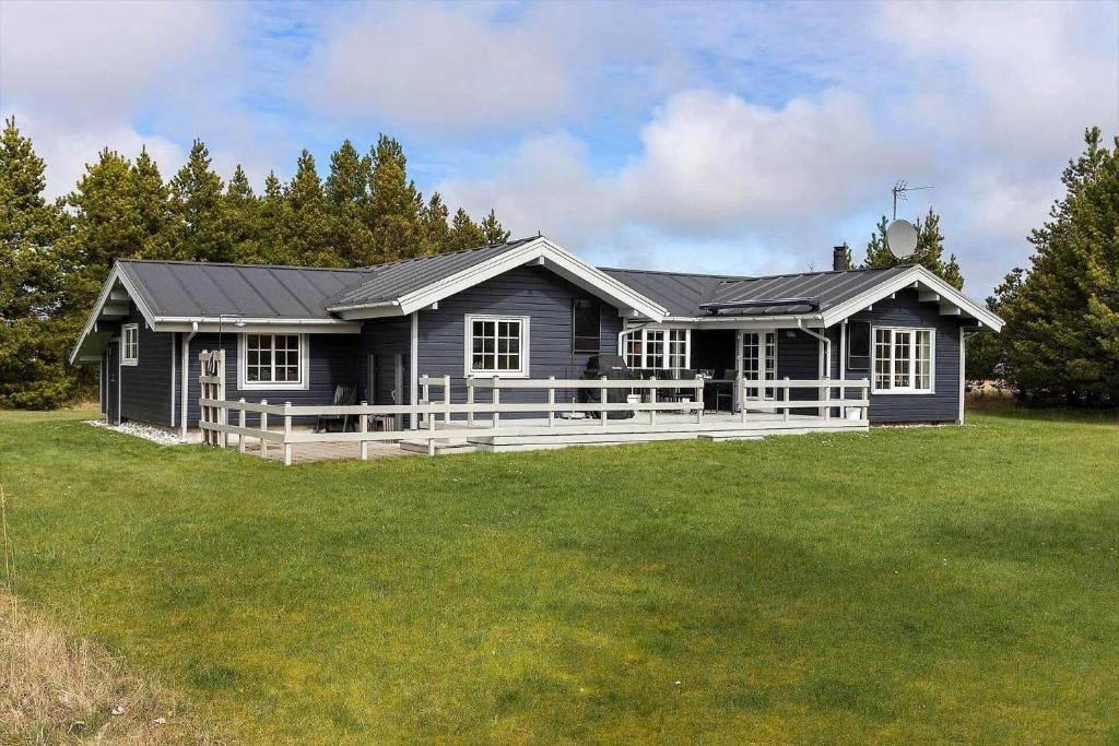 a black house with a porch on a lawn at TV1295-Bindslev-Uglevej-6 in Bindslev