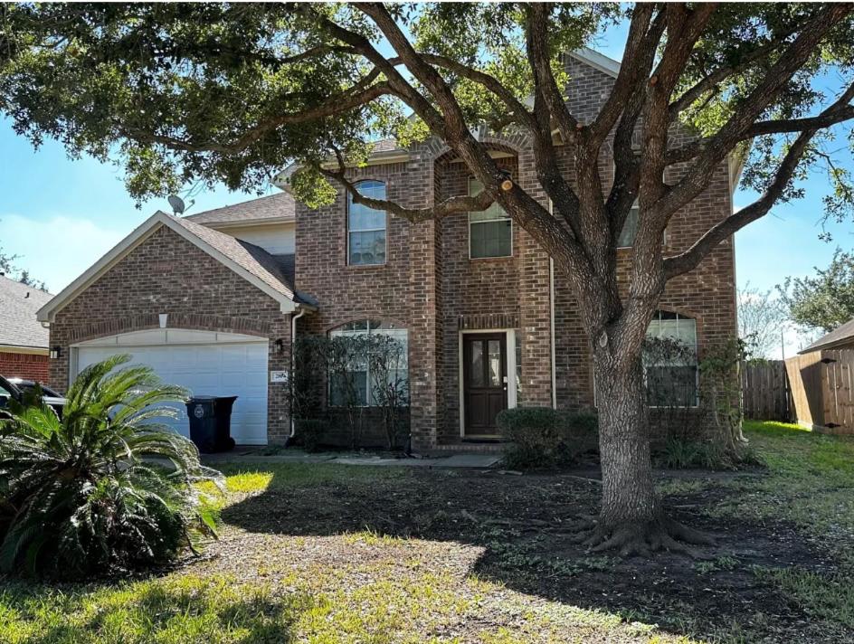 a brick house with a tree in the yard at home sweet home in Sugar Land