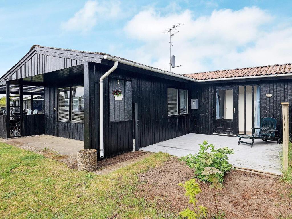 a black house with a porch and a patio at Holiday home in Sæby near beach in Sæby