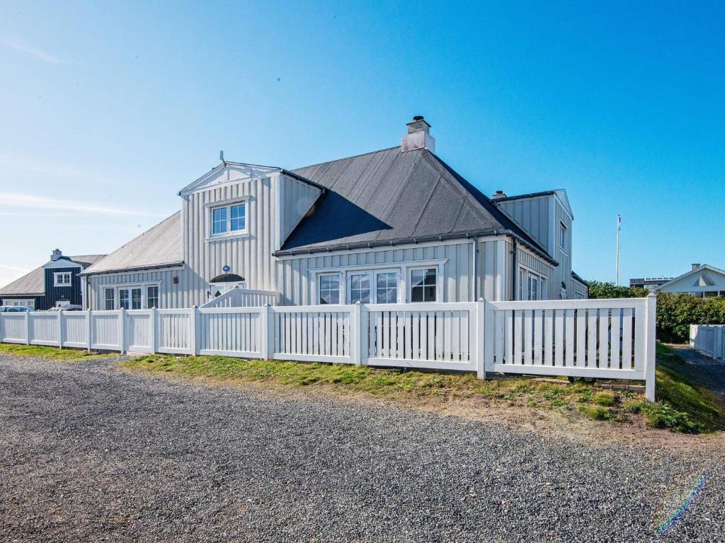 a white fence in front of a white house at 6 person holiday home in Ringkøbing in Ringkøbing