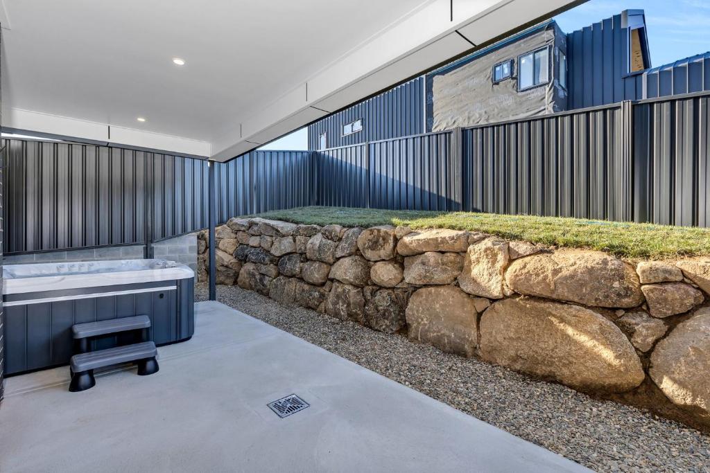 y baño con pared de piedra y bañera. en 14 Abbott Street - Unit, en Jindabyne