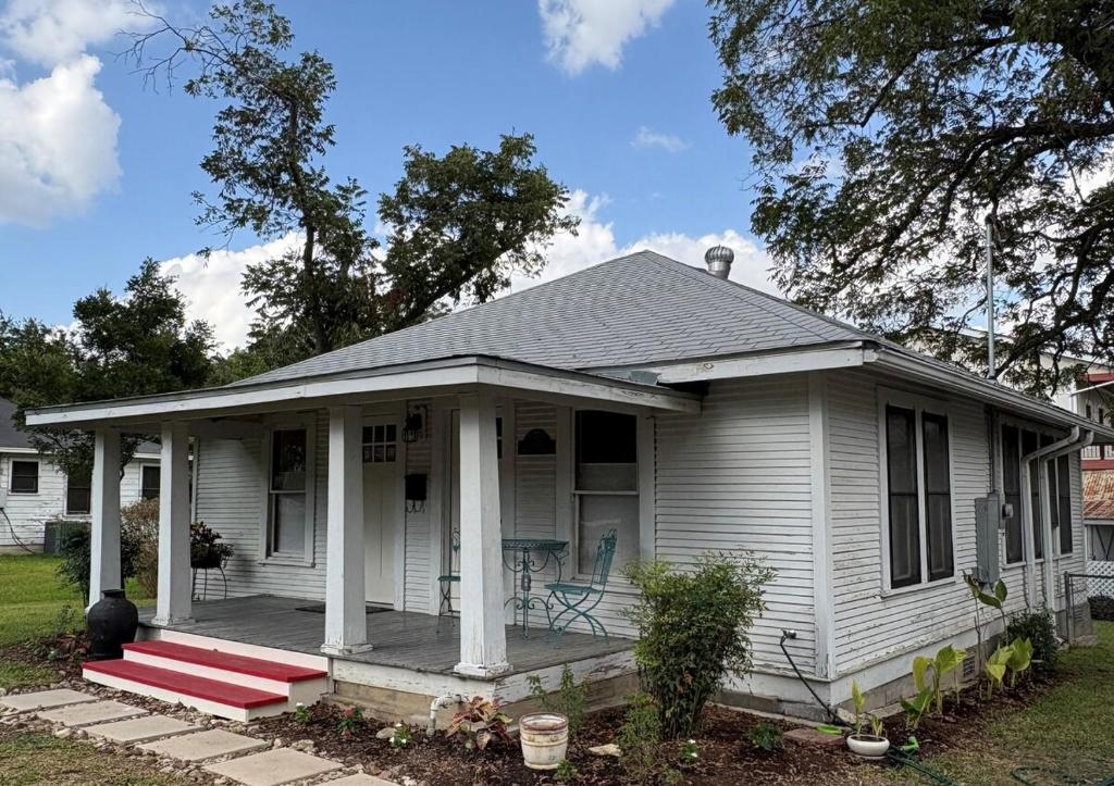 una casa bianca con portico con panchina rossa di Historic bungalow on Church Street a Georgetown