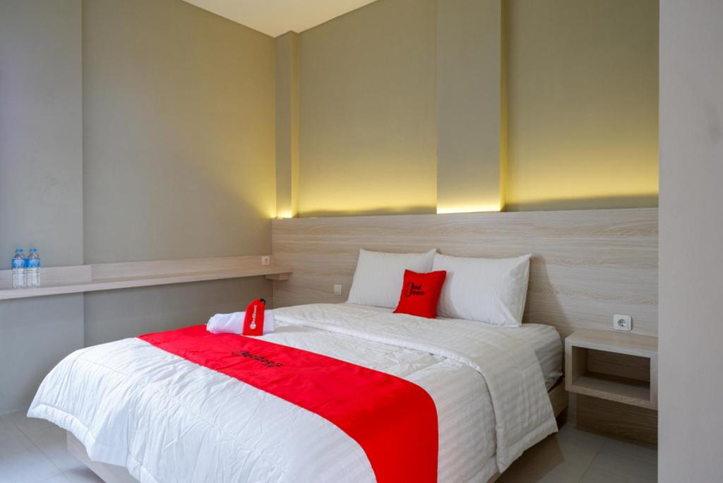 a bedroom with a white bed with red pillows at RedDoorz Near PRPP Marina Semarang in Kalibanteng-lor