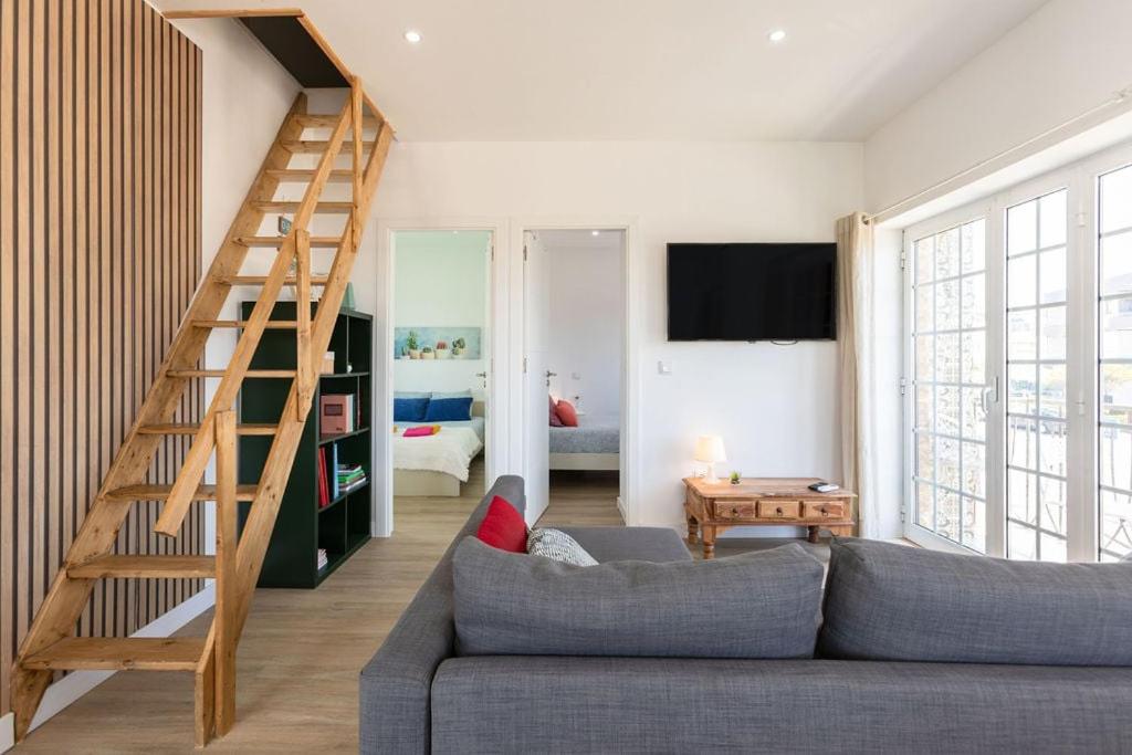 a living room with a couch and a wooden staircase at Beach House - Terrace sea sunset in Labruge
