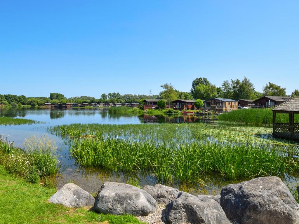 a pond with rocks and houses in the background at Sunnybank in Warton