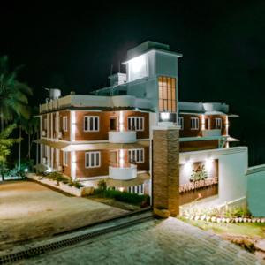 a large house with lights on it at night at Wayanad Farm Heritage in Sultan Bathery