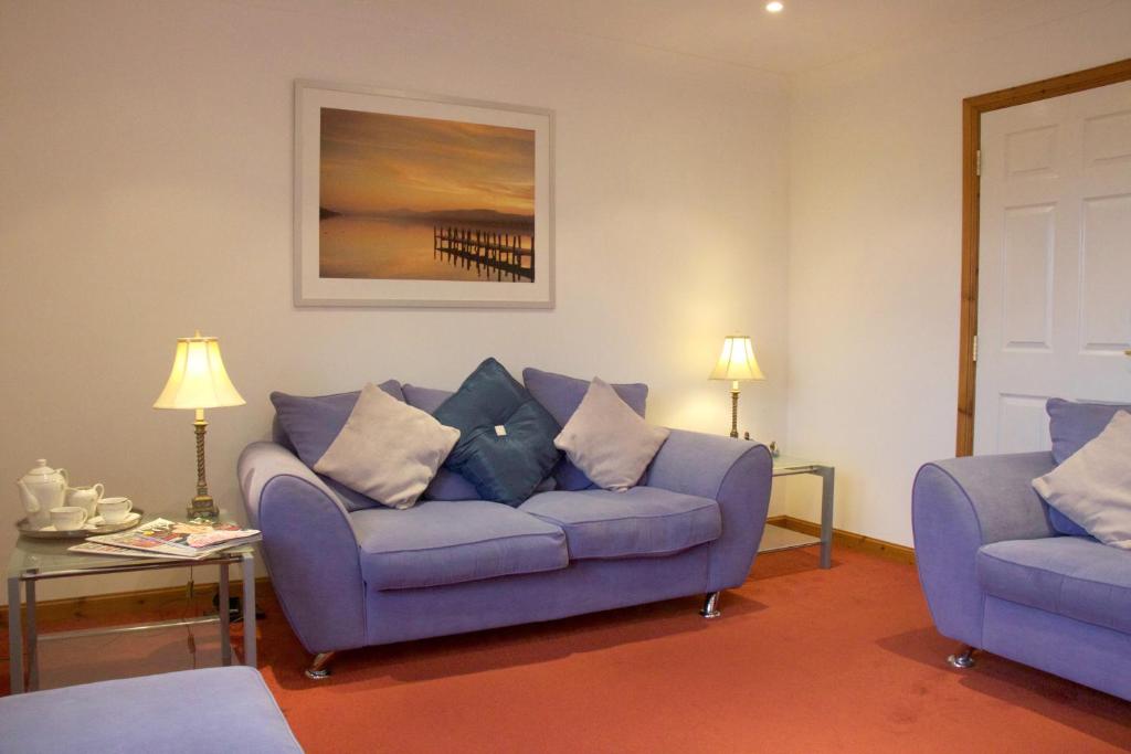 a living room with a blue couch and a table at Pintail Apartment Bamburgh in Bamburgh