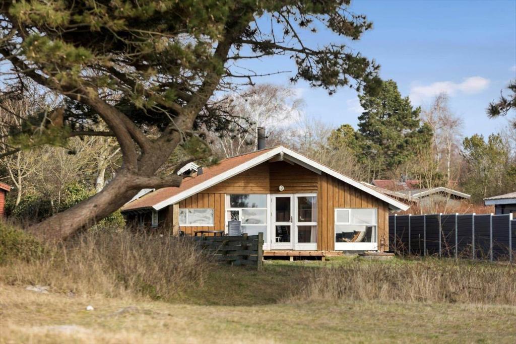a small wooden house in a field with a tree at SB113-Sydals-Oddermosen-11 in Sønderby