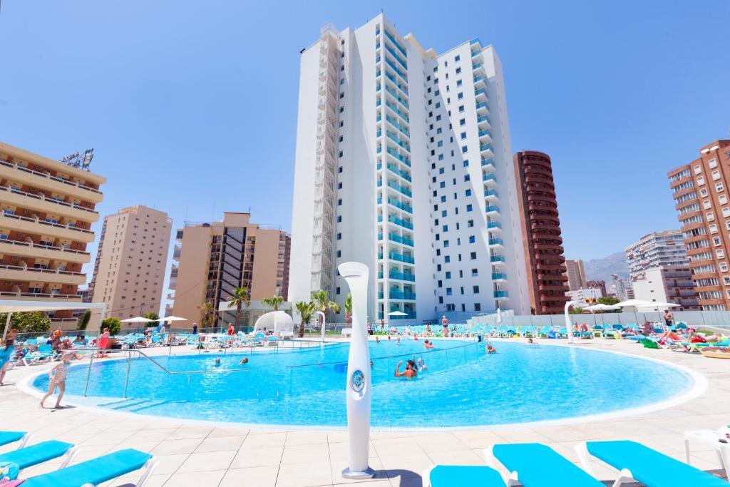 uma grande piscina com cadeiras azuis e edifícios em Port Benidorm Hotel & Spa 4* Sup em Benidorm