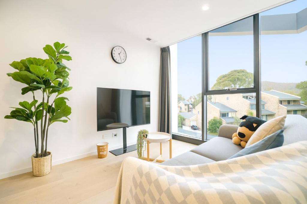 a living room with a couch and a large window at Easeful Canberra CBD 2BR Apt in Canberra