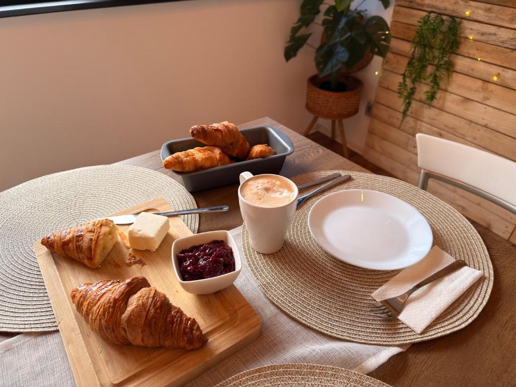 a table with a plate of pastries and a cup of coffee at City Center & Free Parking - Rest & Nest Boho Deluxe Apartment in Debrecen