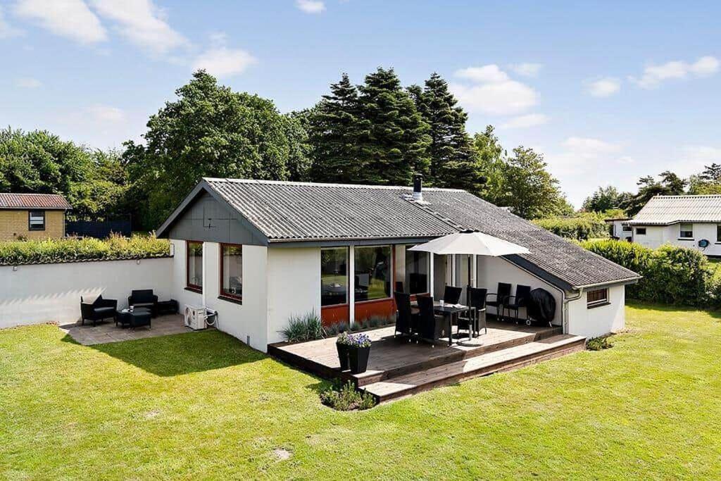 een klein huis met een terras met stoelen en een parasol bij SB50301-Sydals-Solbjergvej-7 in Sønderby