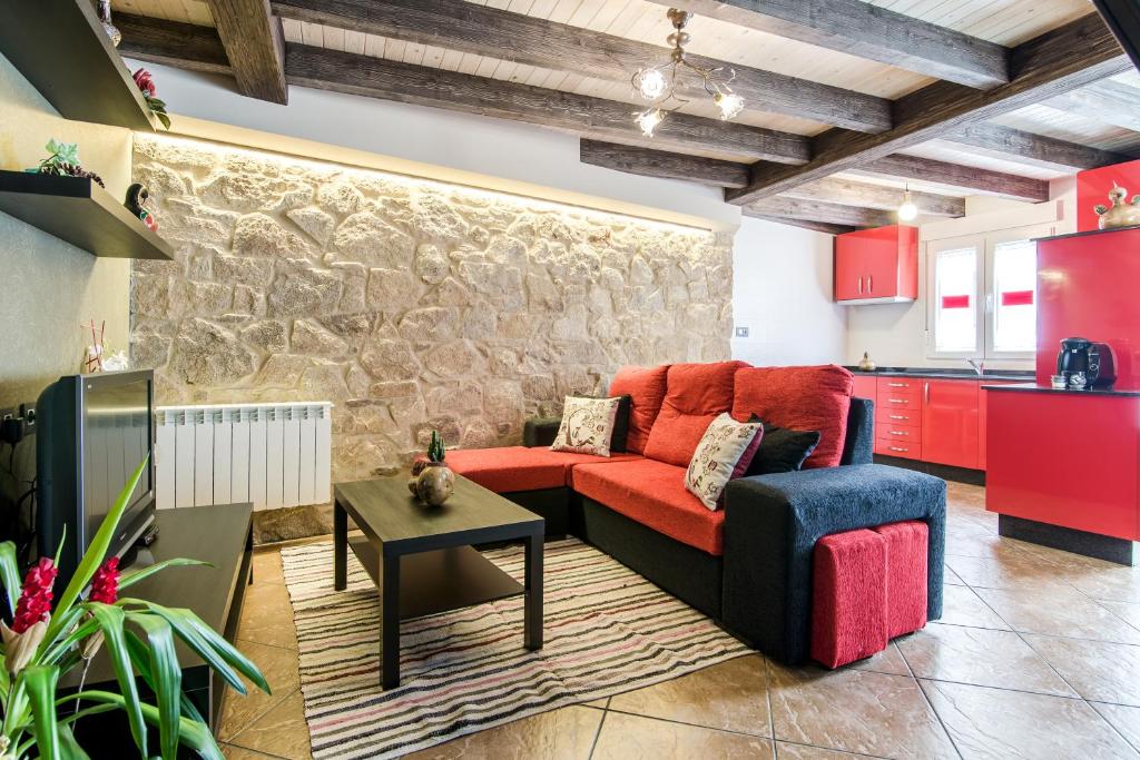 a living room with a red couch and a stone wall at Casa Carla in Palas de Rei 