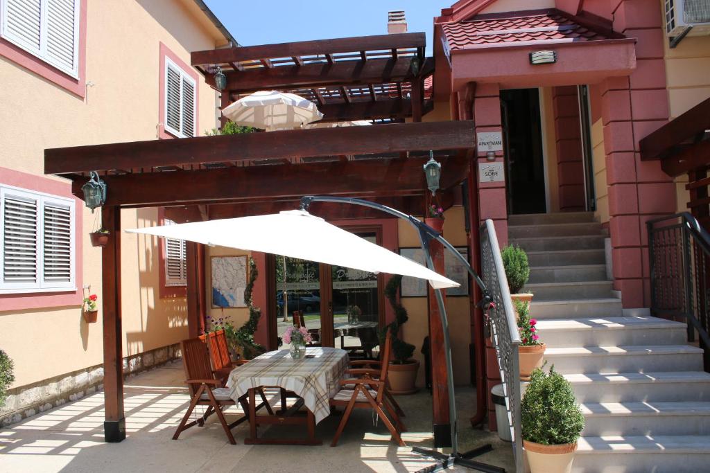 a table with a white umbrella in front of a house at Apartments Dragović Nikšić in Nikšić