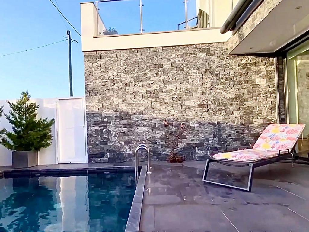 a patio with a chair and a swimming pool at Aroeira Luxury Azul Villa, Lisboa, Beach, Surfing, Golf, Exploring, Hiking, Fishing in Charneca