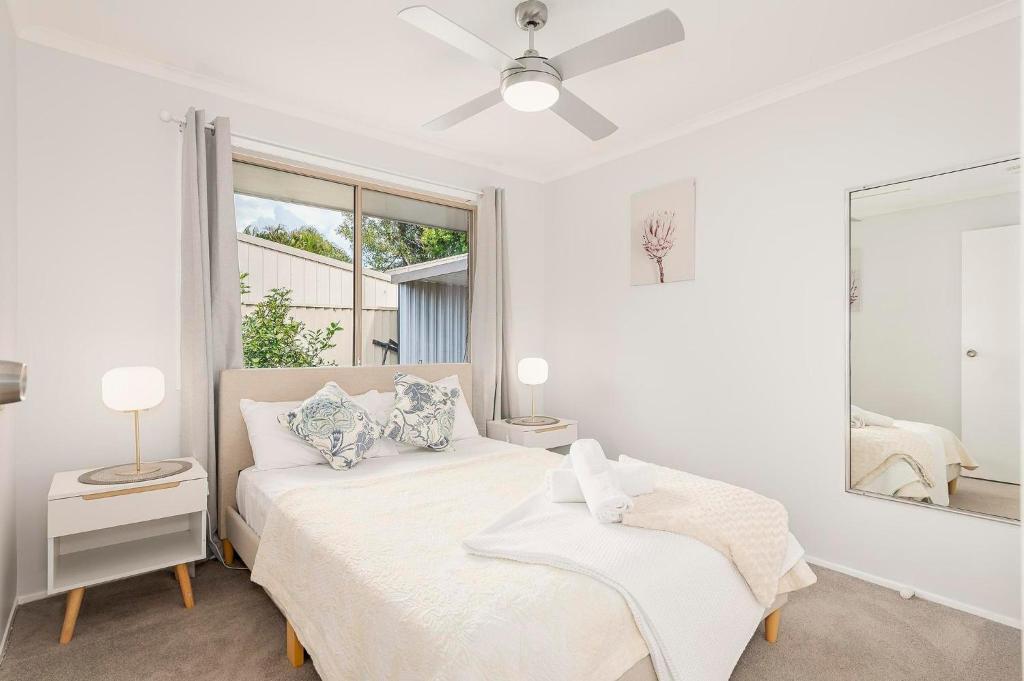 a white bedroom with a bed and a window at Pet friendly Gold Coast holiday home, Sleeps 7, 10min walk to 'Wet n Wild' in Gold Coast