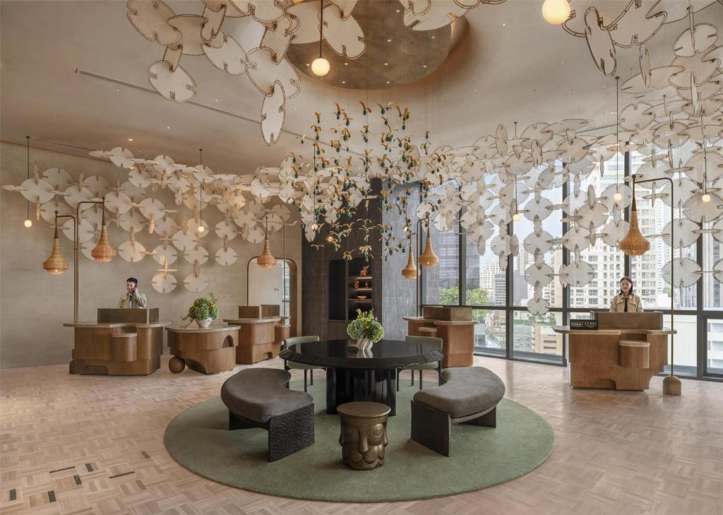 A reception lounge with curved benches sits beneath a dense sculptural ceiling display.