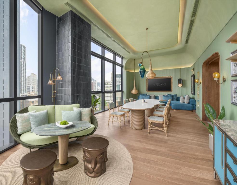 A colorful high-rise lounge with window seating, dining tables, and city views.