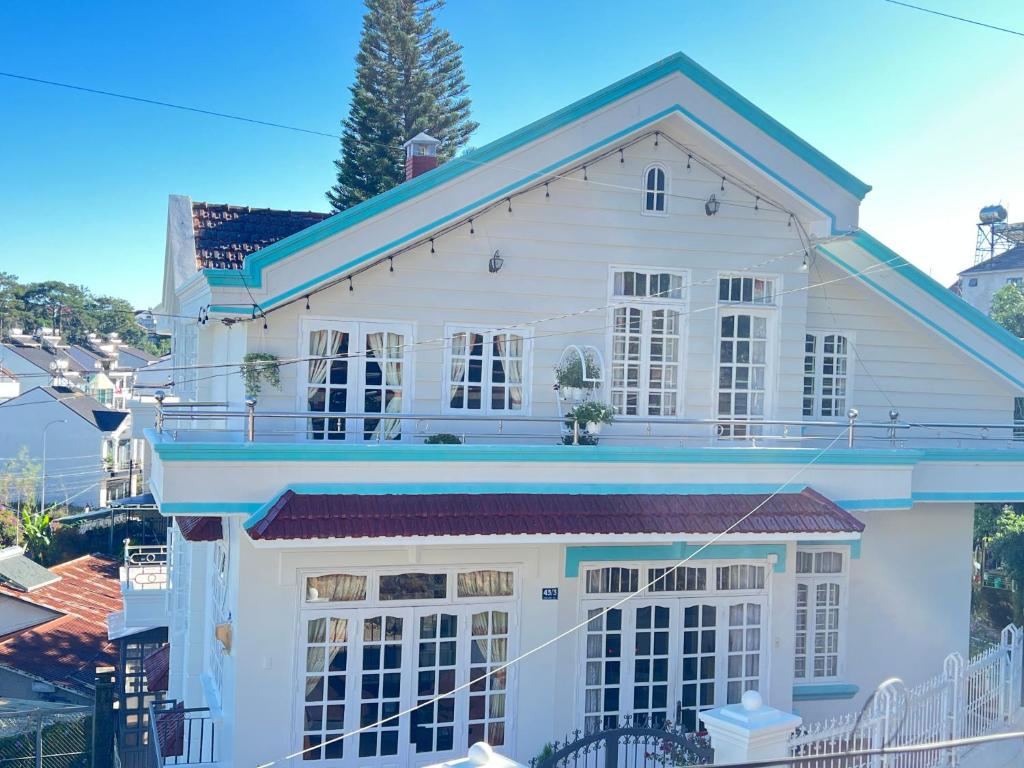 Casa blanca con techo azul en Homestay Nhà Bi, en Da Lat