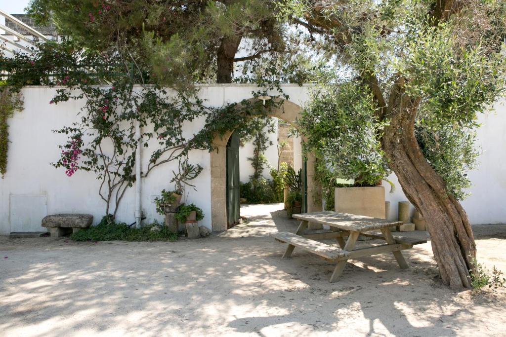 una mesa de picnic bajo un árbol al lado de un edificio en Masseria Nanni, en Gallipoli