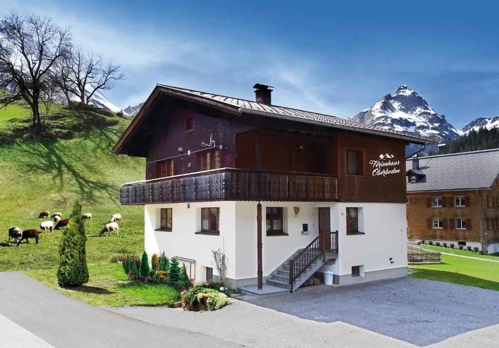 a building with sheep in a field with a mountain at Ferienhaus Oberboden in Schröcken