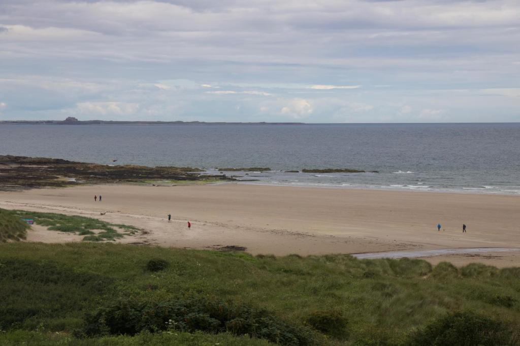 a group of people walking on a beach at Pintail Apartment Bamburgh in Bamburgh