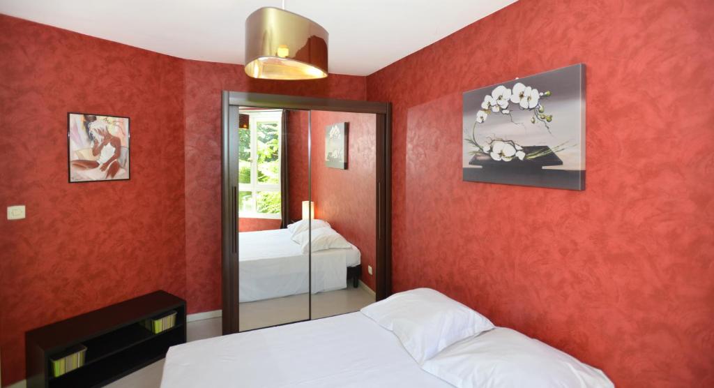 a bedroom with red walls with two beds and a mirror at Appart&#39; Rachais in Lyon