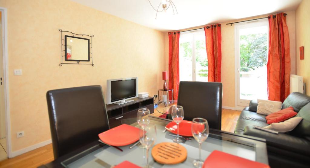 a living room with a glass table with red chairs at Appart&#39; Rachais in Lyon