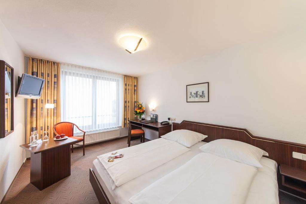ヴォルフスブルクにあるHotel Strijewskiの大きなベッドと机があるホテルの部屋