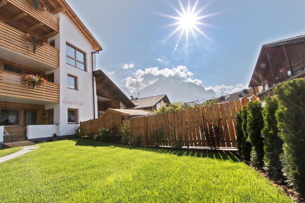 a backyard with a wooden fence and green grass at Apartments Ciasa Costa in Badia
