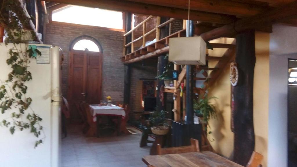 un comedor con mesa y escalera y una habitación con nevera en Casa Marisa en Los Reartes
