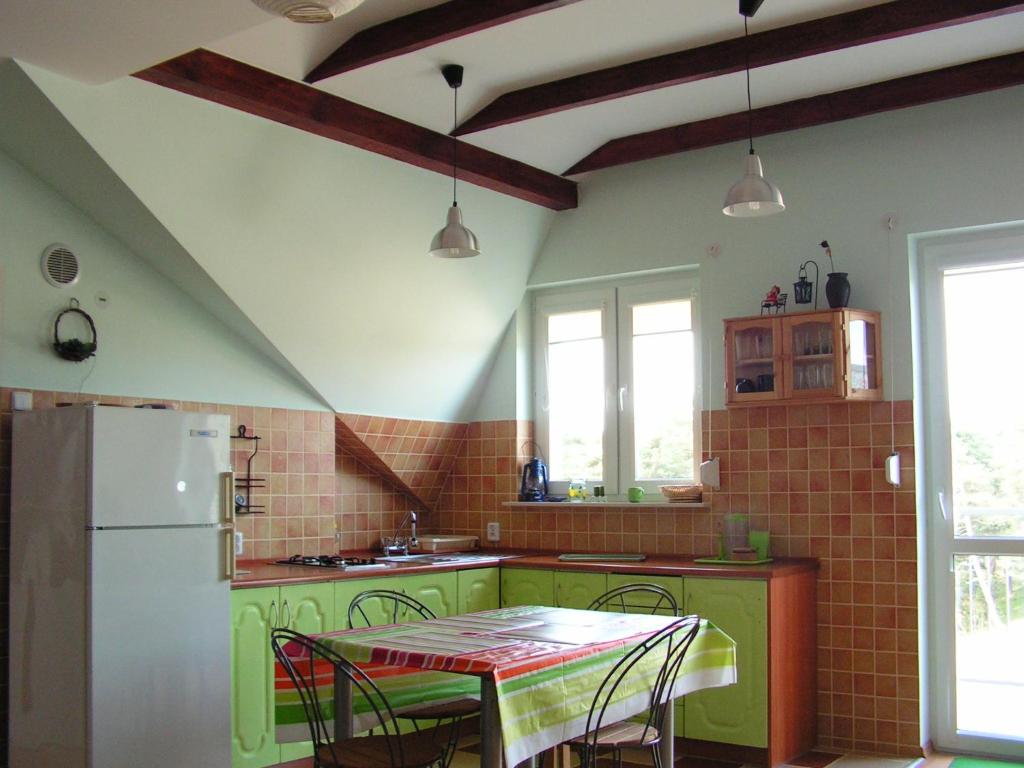 een keuken met groene kasten en een tafel met stoelen bij Apartament Paula in Ustka