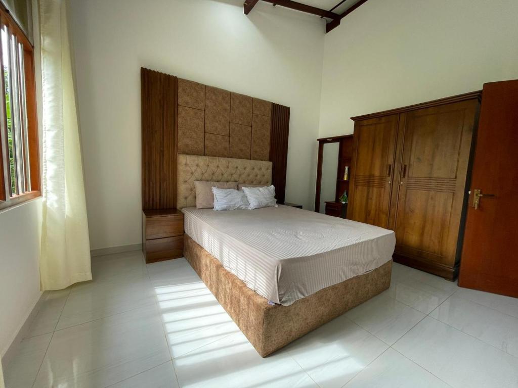 a bedroom with a bed and a wooden cabinet at Serene Villa in Beruwala