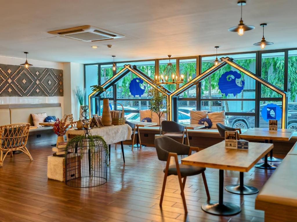 A bright communal lounge offers tables, chairs and window-side seating overlooking greenery.