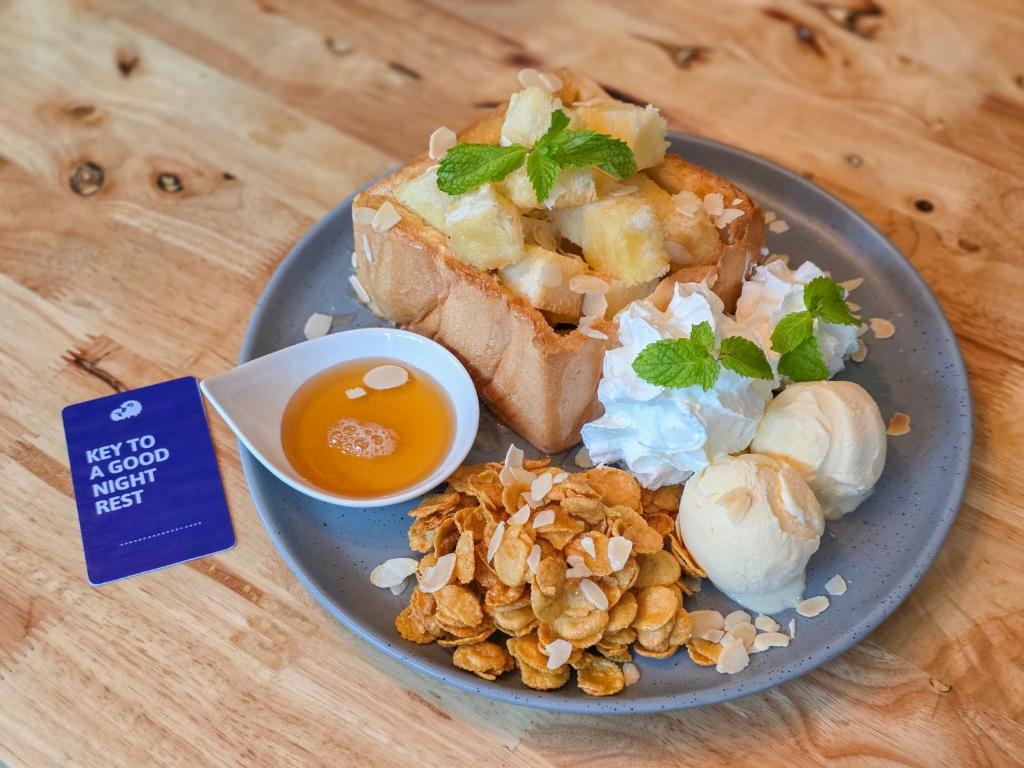 A plated dessert or breakfast dish of toast, fruit, cream, honey, and almonds.