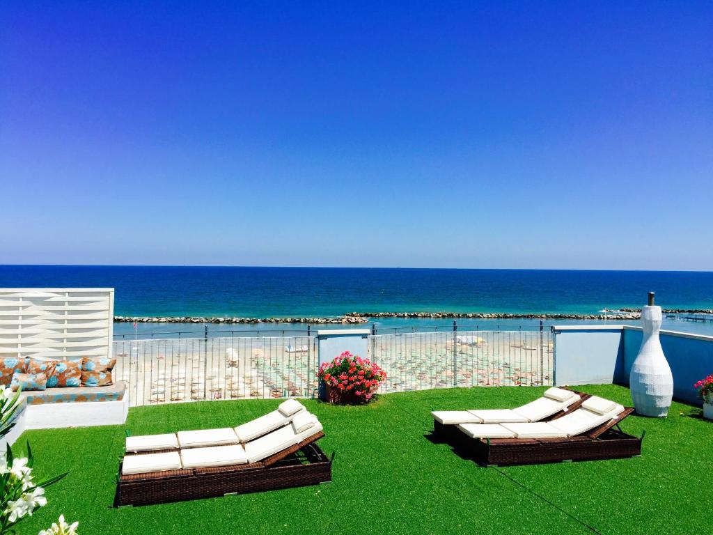 里米尼的住宿－Residence Frontemare，两张白色沙发,坐在靠近大海的草地上