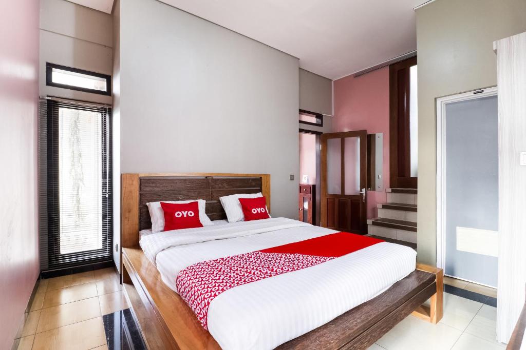 une chambre avec un grand lit avec des oreillers rouges dans l'établissement Hotel O Guest House Teras Waruga Syariah, à Bandung