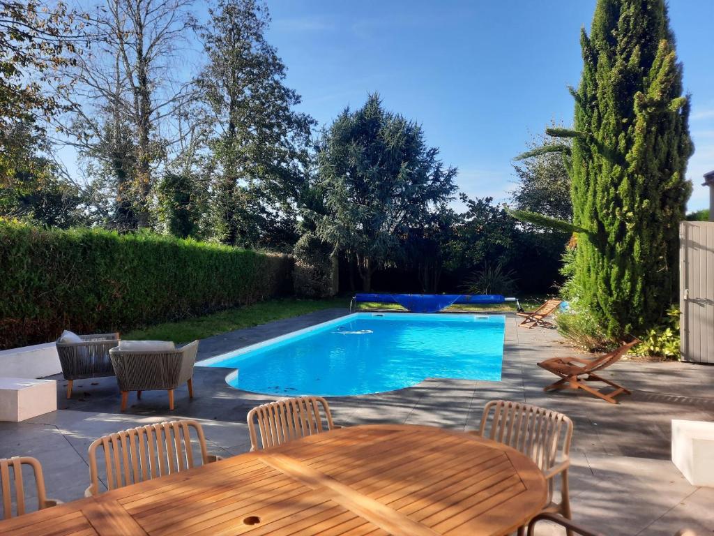 a backyard with a pool and a table and chairs at Villa Au petit baigneur - Maison avec piscine et jardin clos in Challans