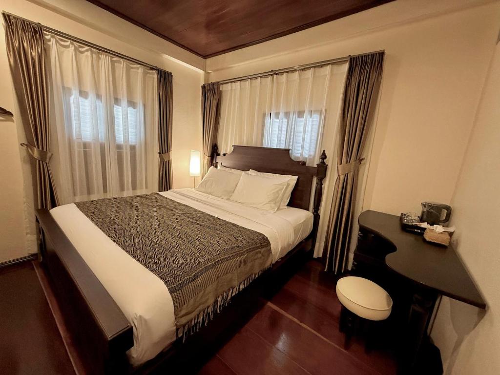a bedroom with a bed and a desk and windows at Onson De Boutique Hotel in Luang Prabang