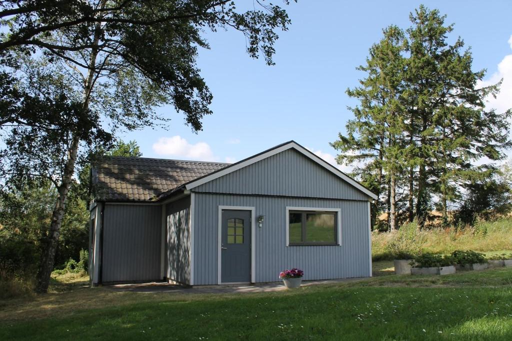 a gray shed with a door in a yard at Gäststuga på landsbyggden utanför L Alstad in Trelleborg
