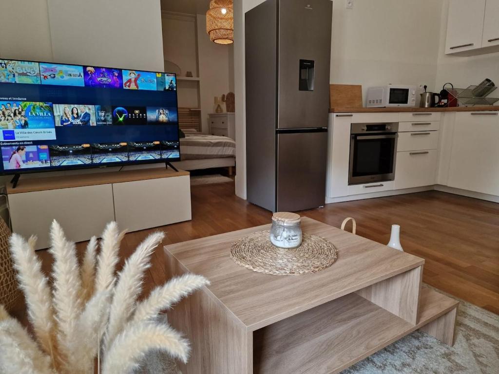 a living room with a table and a large tv at Appartement T2 - Centre-ville in Saint-Pourçain-sur-Sioule