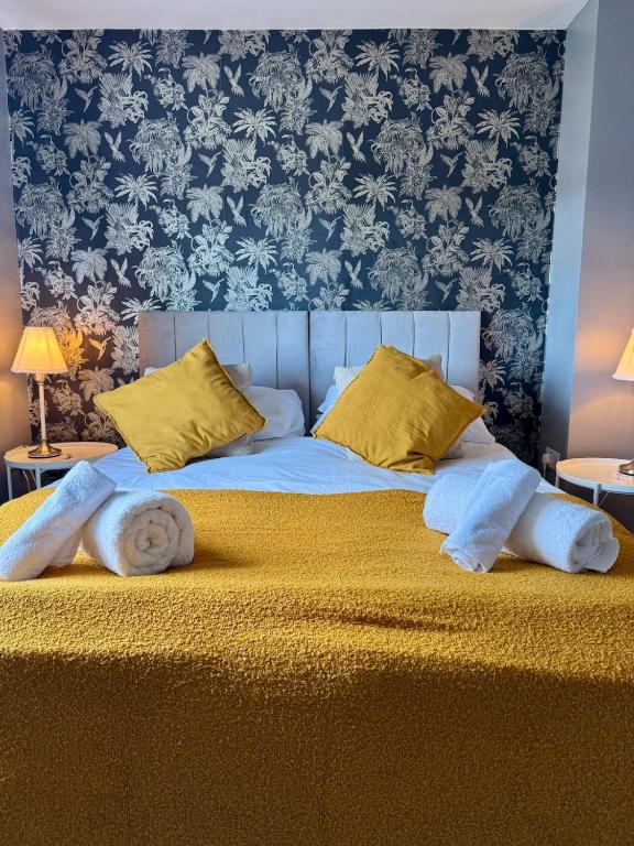 a large bed with yellow pillows and a blue wall at Home in between Bath and Bristol - Sleeps 9 guests in Keynsham